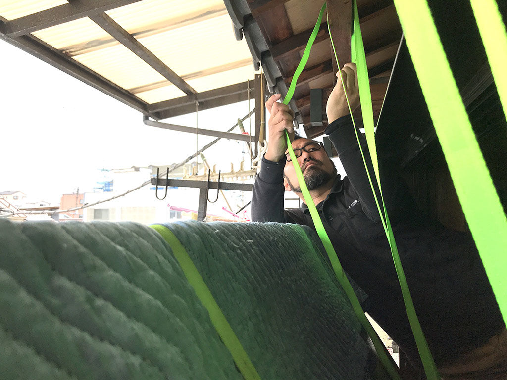 家具を吊り降ろしするためにベルトを庇に巻き付ける