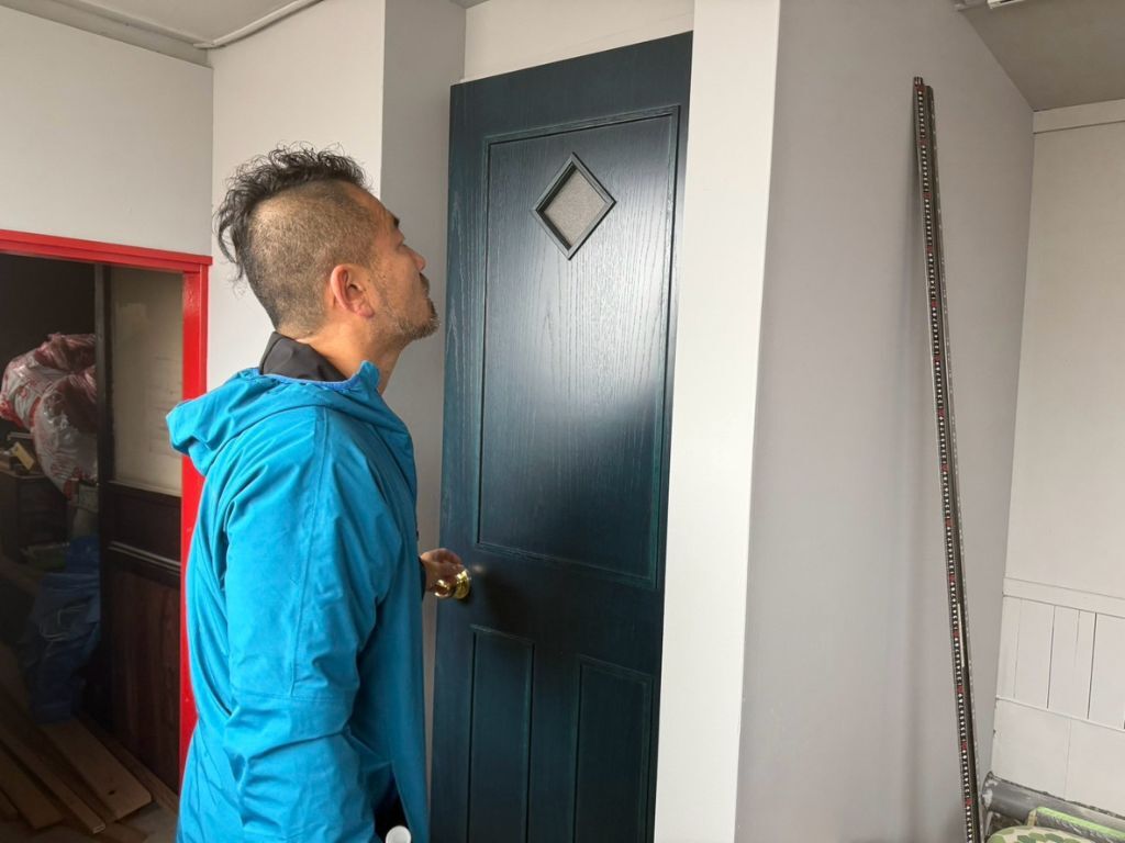 アカリスタンドのトイレのドアの前に佇む家具作りたいおっさん